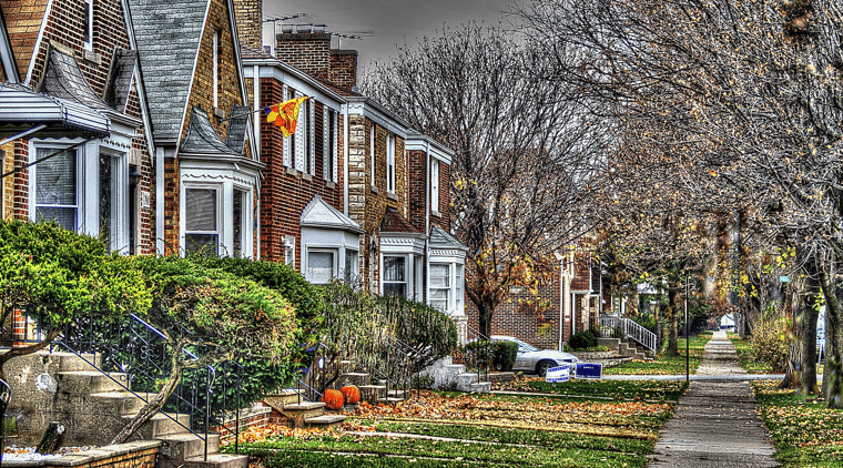 Row of small brick home with front stairs and bushes