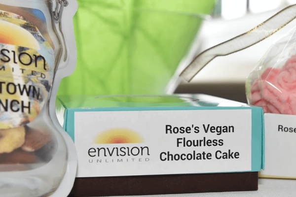 Bake sale items on display, centered on a blue box with a white label featuring orange and yellow logo and white text.