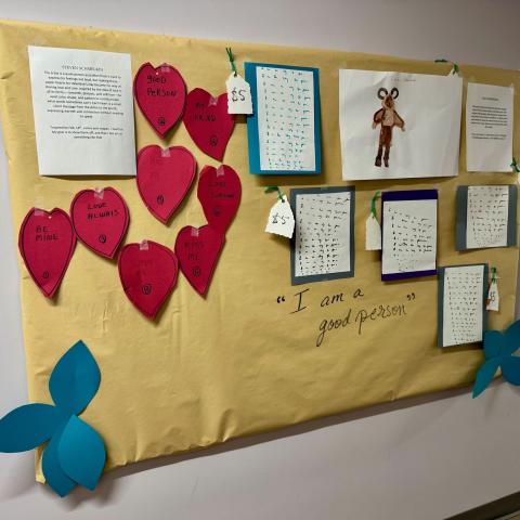 Red hearts and other artwork on a wall.