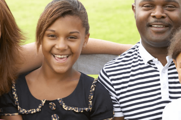 outdoors racial diverse family photo with two parents and three young children all smiling